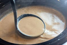 a ladle in a pot filled with food and liquid for making hot chocolates