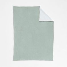 a light green and white blanket folded on top of each other