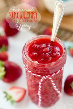 a jar filled with strawberry ice cream sitting on top of a table next to strawberries