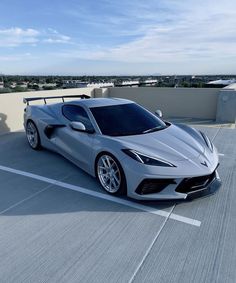 a silver sports car is parked on the roof of an apartment building in front of a parking lot