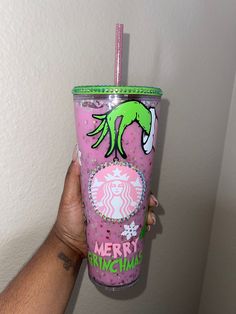 a person holding up a pink starbucks cup with the words merry grinen on it