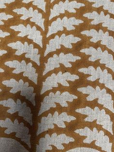 an orange and white patterned fabric with small leaves on the side, as well as a pattern