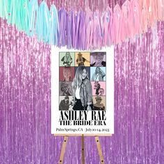 an easel stands in front of a purple backdrop with streamers and a poster