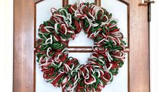 a wreath is hanging on the front door with red, white and green streamers