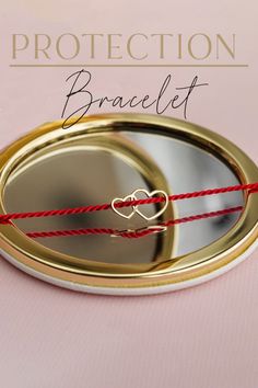 a close up of a mirror with red string on it and the words protection bracelet