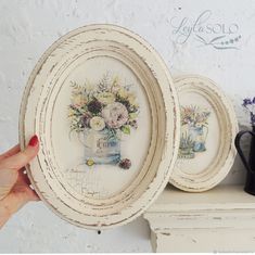 two plates with flowers painted on them are sitting on a shelf next to a mug