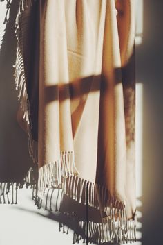 the blanket is hanging up against the wall with sunlight coming through it and shadows on the fabric