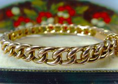 Antique Victorian gold Bangle, the bangle is crafted in 9ct rose gold,  a true warm red gold in colour, in a continuous sturdy chunky curb link that sits upon an interior double frame, the bangle is a heavy 16.1 grams, super quality, in very good condition with only light signs of wear, with very shallow indentations to one side, nothing, and does not distract, with a gold safety chain attached, interior size measures 58 mm across and 50 mm top to bottom, 7.5 mm wide, marked 9ct, suit small or m Classic Gold Curb Chain Bangle Bracelet, Classic Gold Bangle Bracelet With Curb Chain, Gold Curb Chain Bangle Bracelet, Double Frame, Victorian Gold, Warm Red, Safety Chain, Gold Bangle, Luxury Boxes