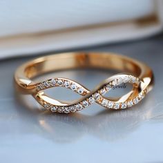 a gold wedding band with diamonds on the side and an elegant twist in the middle