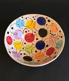 a multicolored bowl with black dots and circles on the bottom is sitting on a table