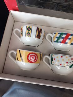 three cups in a box with designs on them