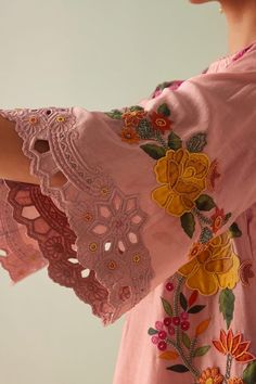 a close up of a person wearing a pink dress with flowers on it and lace