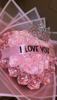 a tiara on top of a pink box with roses in it that says i love you