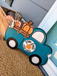 a blue wooden car with pumpkins on it sitting in front of a door way