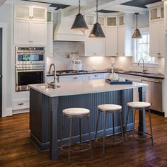 a kitchen with an island and three stools next to the stove top oven in it