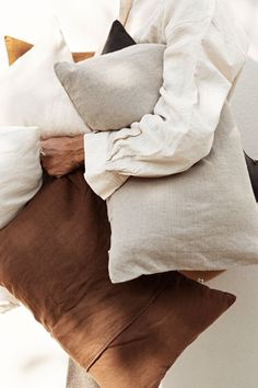 a person holding several pillows in their hands