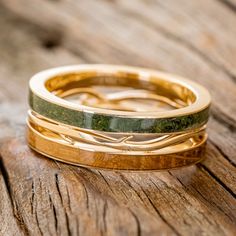 three gold wedding bands with green marble inlays sitting on top of each other