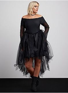 a woman wearing a black dress with sheer tulle on the bottom and long sleeves