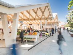 people are walking around an outdoor market with fruits and vegetables on display at the tables