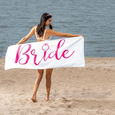 a beautiful woman holding a white sign on top of a beach