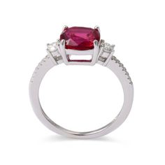 This 3-stone ring is crafted with rhodium over 925 Sterling Silver. The engagement ring style features a cushion-cut lab-grown ruby measuring 8x8mm as the centerpiece. It is complemented by two 3mm round moissanite stones and fourteen 1.0mm round moissanite stones. Three Stone Cushion Cut Ring, White Gold Cushion Cut Ruby Ring With Prong Setting, Ruby Rings With Cushion Cut And Accent Stones, Ruby Rings With Accent Stones In Cushion Cut, Cushion Cut Ruby Wedding Ring, Red Cushion Cut Ring With Accent Stones, Silver Cushion Cut Ruby Ring With Prong Setting, Silver Ruby Ring With Cushion Cut Halo Setting, Three Stone Classic Jewelry With Lab-created Ruby