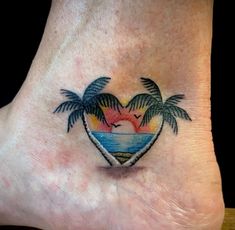 a heart shaped tattoo with palm trees on the bottom of its foot and an ocean scene in the middle