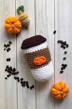 crocheted coffee cup cozyie with pumpkins and beans on the side next to it