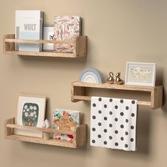 two wooden shelves with pictures, cards and other items on them against a beige wall