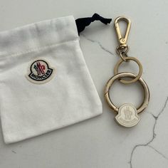 a keychain with a badge on it sitting next to a white pocket bag