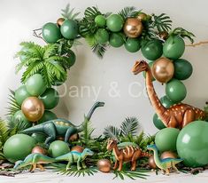 an image of dinosaurs and balloons in the middle of a birthday party setting with greenery