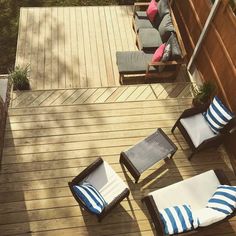 an overhead view of a wooden deck with chairs and cushions on it, looking down at the back yard