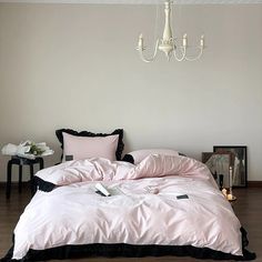 a bed with pink and black comforters in a room next to a chandelier