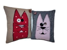 two decorative pillows with cats on them, one is red and the other is blue