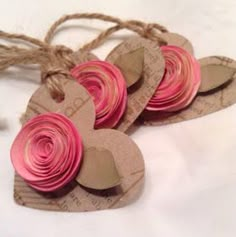 four heart shaped tags with pink and brown paper flowers on them, tied to twine