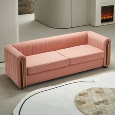 a pink couch sitting on top of a white rug next to a fire place in a living room