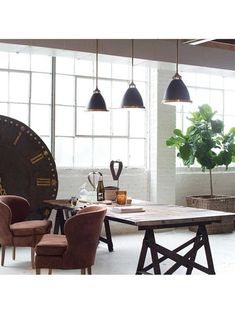 a table with chairs and a clock on the wall in an industrial style living room