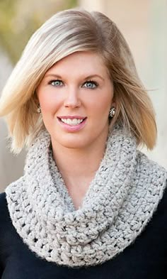 a woman with blonde hair wearing a gray cowl