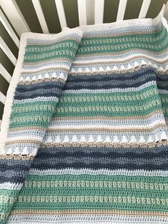 a crocheted blanket sitting on top of a bed next to a white chair