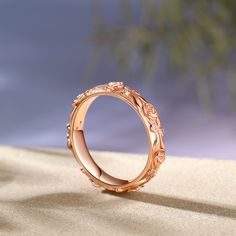 a rose gold wedding ring on top of sand