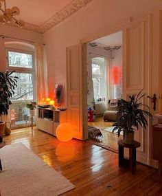 a living room filled with lots of furniture and plants on top of a hard wood floor