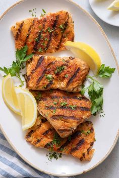 grilled fish with lemon and parsley on a white plate