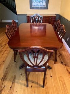 a wooden table with chairs around it in the middle of a wood floored room