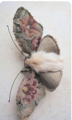 two pieces of fabric with flowers and feathers attached to each other on a white surface