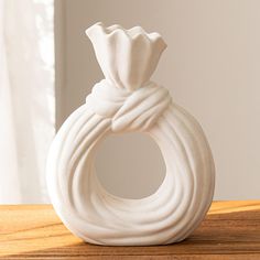 a white vase sitting on top of a wooden table