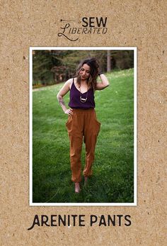 a woman standing in the grass with her hands on her hips and wearing brown pants