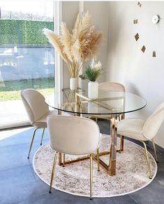 a glass table with chairs around it in front of a large window and a clock on the wall