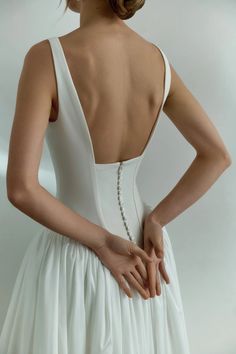 the back of a woman's wedding dress, with her hands on her hip