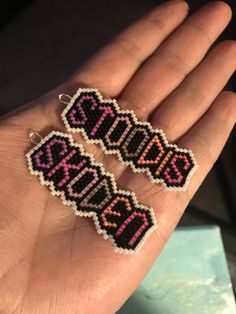 two handmade beaded earrings with the word survivor written on them in pink and black