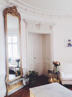 a living room filled with furniture and a large mirror on the wall next to a couch