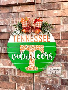 a wooden sign that says tennessee on the side of a brick wall with a bow